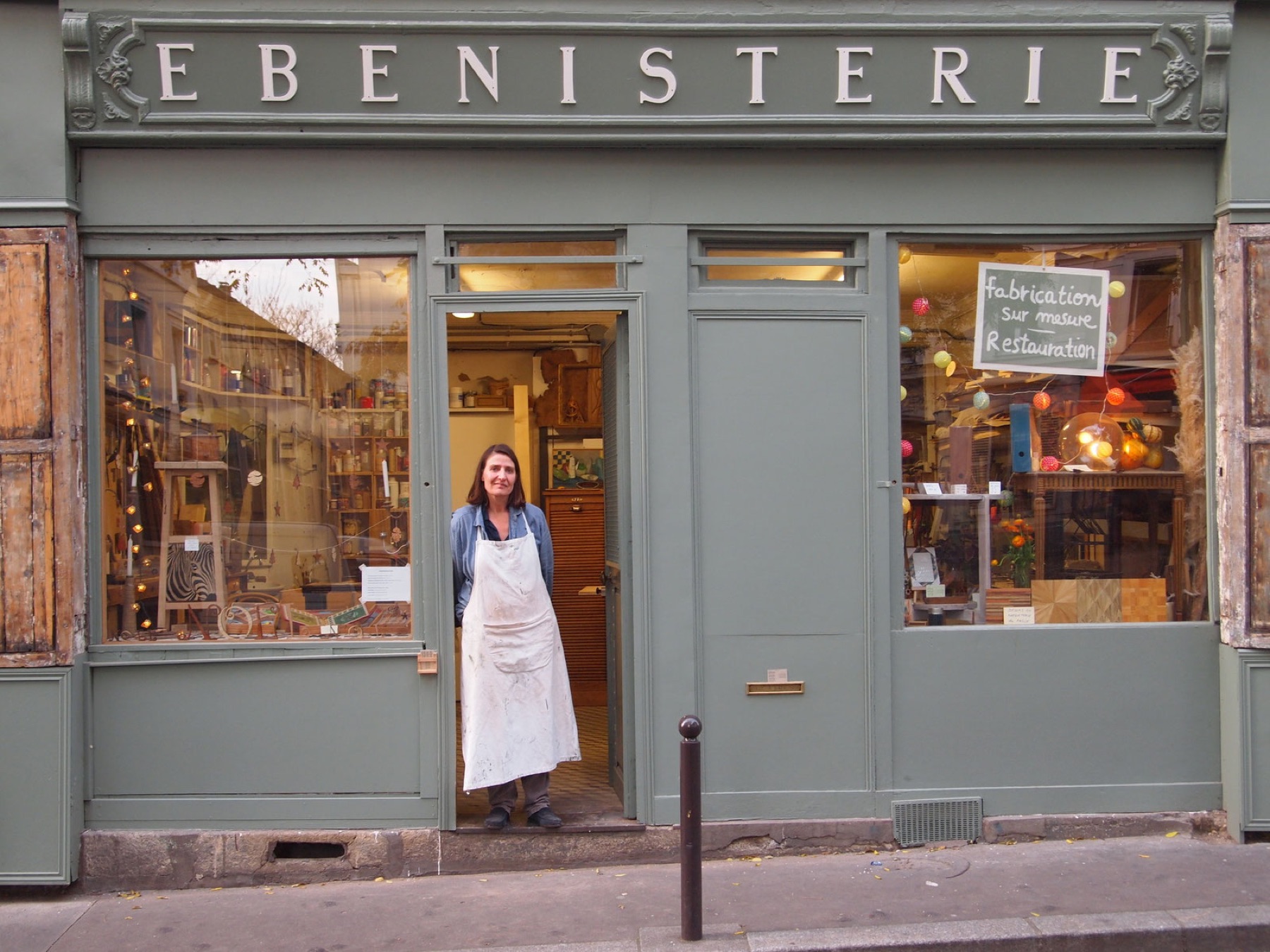 Geneviève de Divonne sur le pas de la porte de son atelier d'ébénisterie, rue Sainte-Marthe